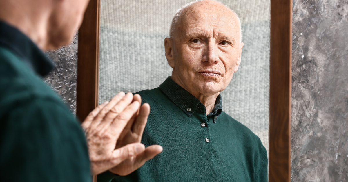 An older man looking into a mirror